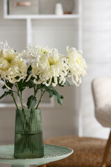 Beautiful white chrysanthemum flowers in vase on coffee table indoors