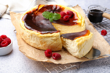 Tasty Basque cheesecake with raspberries and mint on light grey textured table, closeup