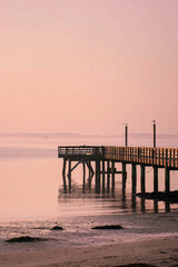 Fototapeta premium Distant Pier Silhouette over Ocean with Expansive Negative Space and Tranquil Sky – perfect for beach wall decor 