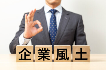 「企業風土」と書かれたブロックとOKポーズをするビジネスマン