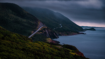 Moody coastal view of the Cabot Trail in Cape Breton, Nova Scotia, with a winding road along steep...