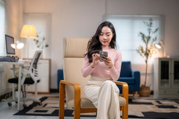 Focused businesswoman browsing on mobile phone while working remotely from home