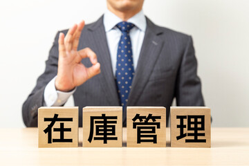 「在庫管理」と書かれたブロックとOKポーズをするビジネスマン