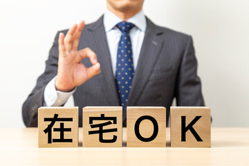 「在宅OK」と書かれたブロックとOKポーズをするビジネスマン