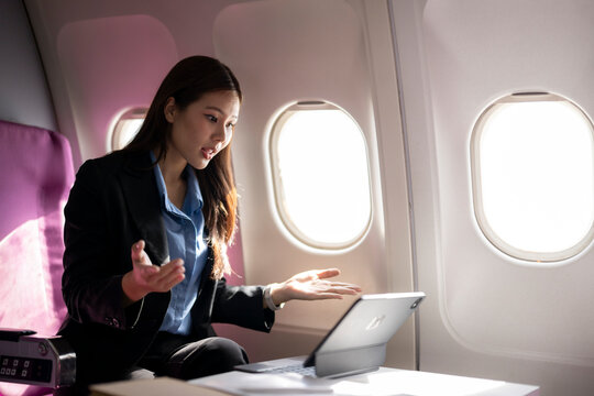 Businesswoman having video call during airplane flight - Powered by Adobe