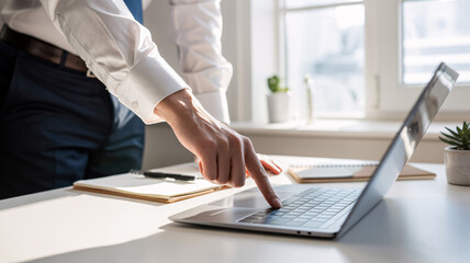 Business professional pressing laptop key in sunlit modern office workspace