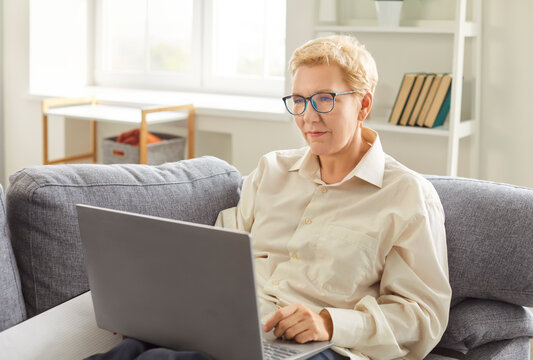 Senior older lady using applications on laptop computer screen, old mature woman chatting in messenger or social network with friends or children, shopping in internet store, smiling surfing online
