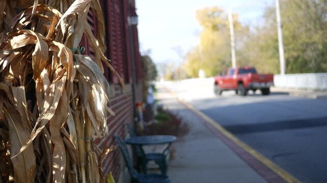 Scene Setter Shot of Red Truck Driving in Autumn in Small Town