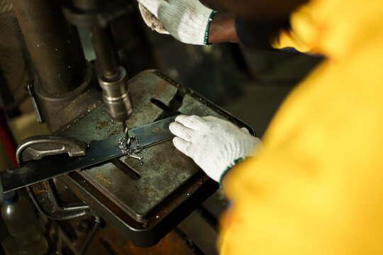 African American male metal worker operating drill press machine. - Powered by Adobe