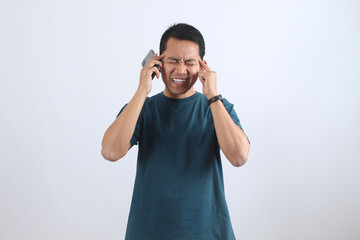Stressed Asian man with headache on difficult phone call