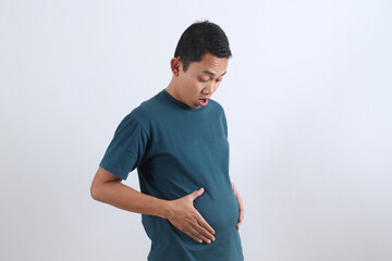Shocked man looking at his bloated stomach. Weight gain problem.