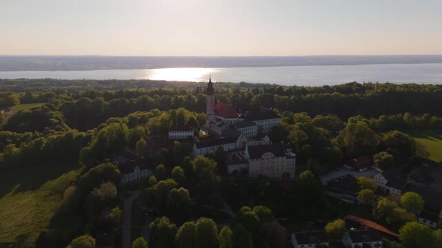 Aerial drone video of Kloster Andechs and pilgrimage church on Holy Mountain by Lake Ammersee, Bavaria, Germany. Scenic sunset view of monastery, nature, and rural landscape near Munich