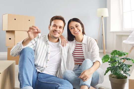 Portrait of a happy family, wife and husband, couple celebrating new home ownership, holding keys during relocation to an apartment or estate. Symbolizing joy, future, and transition.