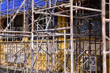 Scaffolding for building repair, A construction worker assembling scaffolding around  