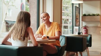 A young girl and her grandmother enjoy precious moments together at a cafe. They engage in conversation and share laughter, creating lasting memories.