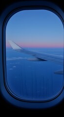 Fototapeta premium Airplane window view reveals a wing gliding over the clouds during a colorful sunset.