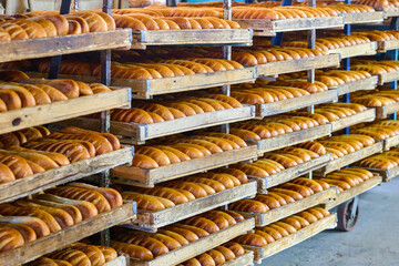 Freshly baked bread rolls cool on wooden trays in a cozy bakery after being pulled from the oven