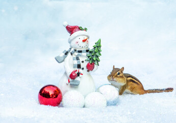 Chipmunk watches a cute snowman in this seasonal Christmas scene in winter 