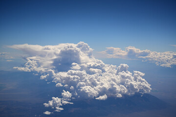 Aerial View of Towering Cumulus Clouds Over Desert Landscape and Mountains