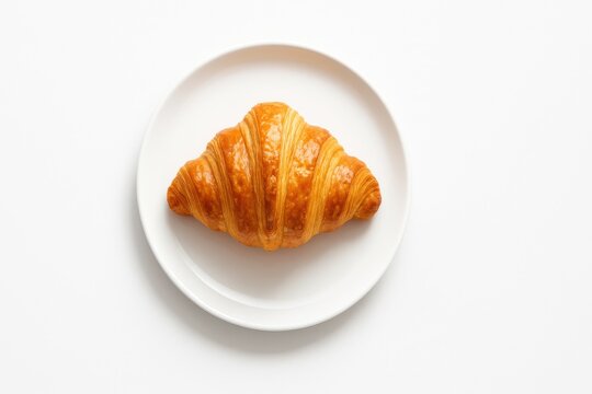 Classic croissant centered on a simple white porcelain plate with a soft gloss bakery studio on pure white