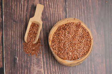 Brown flaxseeds in a wooden bowl and scoop on a table