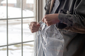 Hands are Unfolding plastic sheeting for insulation on windows, used to help keep heat in a home during winter 