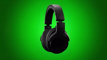 A pair of black over ear headphones are displayed against a green background in a studio shot