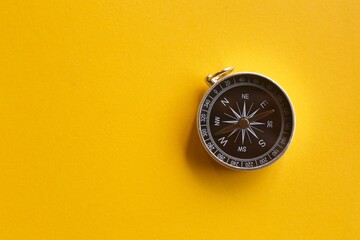 Close up vintage compass on yellow background