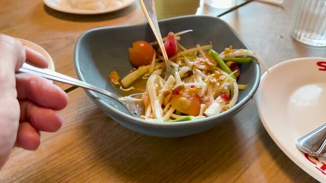 Scooping Thai Green Papaya Salad at Restaurant Table