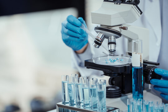 Team of Asian scientists working in modern laboratory equipped microscopes, chemical reagents, conducting advanced research in biochemistry, molecular biology, microbiology, pharmaceutical innovation