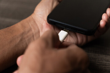 Person Plugging White USB Type C Charger Cable into Black Smartphone