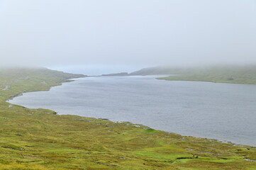 Spectacular Lake Leitisvatn Landscape with Green Pastures and Coastal Scenery in the Faroe Islands
