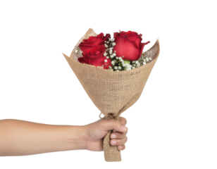 A hand holds a bouquet of red roses wrapped in burlap, adorned with delicate white filler flowers.