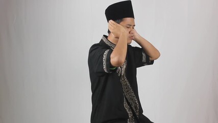 Asian man wearing a black Koko shirt reciting the adhan and iqomah