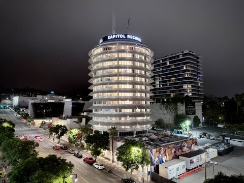 LOS ANGELES, CA, SEP 25, 2025: Wide night view of Capitol Records tower glowing against dark sky, surrounded by Hollywood streets and neighboring buildings. Horizontal view