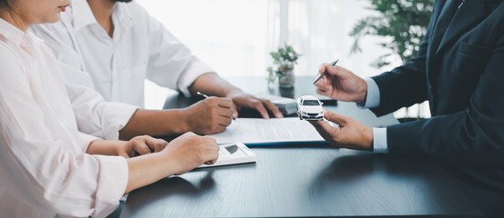 Panorama view of car loan agreement signing with dealer presenting vehicle model, customer using...
