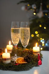 Sparkling champagne in glasses with candle wreath, celebrating Christmas in warm romantic setting.