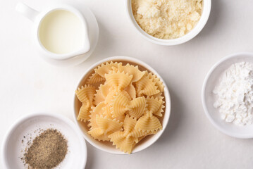 Farfalle pasta with cheese and black pepper, ingredients for Italian cooking on white background