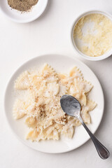 Farfalle pasta with white cream cheese sauce and black pepper, Italian food on a white plate