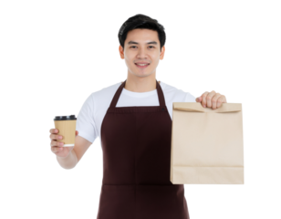 A smiling man in an apron holds a coffee cup in one hand and a paper bag in the other, presenting a welcoming demeanor.