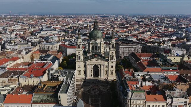 Drone view of St. Stephen&rsquo;s Basilica surrounded by red-roofed Budapest buildings, blending neoclassical beauty with urban life.