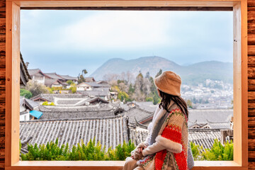 Young female tourist looking at Lijiang Ancient Town, the famous tourist destination in Yunnan Province, China