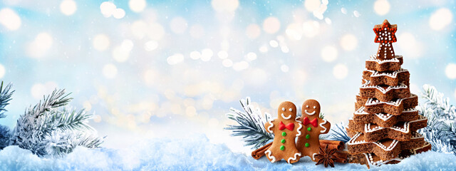 Festive gingerbread cookies and a chocolate Christmas tree made of stacked stars in a snowy, winter...