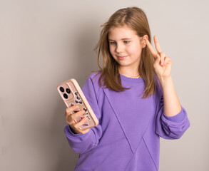 Smiling preteen girl taking a selfie, isolated on grey background. Perfect for technology, social media, youth lifestyle, communication, or modern generation concepts.