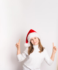Pretty girl in Santa hat and white sweater pointing up to free copy space on white background. Perfect for Christmas advertising, holiday promotions, or festive marketing concepts.