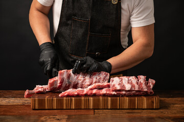 Butcher preparing raw pork ribs on a wooden cutting board