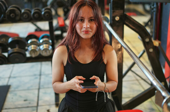 Woman taking break using smartphone in gym