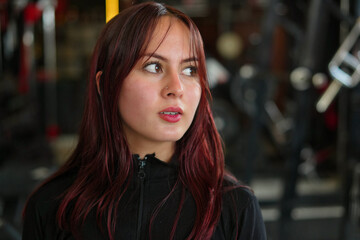 Fototapeta premium Young woman with red hair looking away in gym