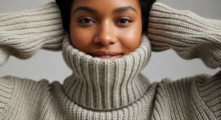 African American woman smiling while wearing a cozy turtleneck sweater, with hands on her head, showcasing warmth and comfort in a soft, inviting atmosphere