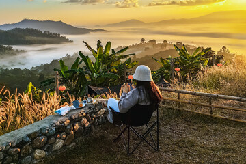 Back view of young female tourist seeing to sea mist and sunrise in winter season on top of mountain with beautiful morning scenic view at Yun Lai viewpoint, Thailand. Travel Adventures Lifestyles.